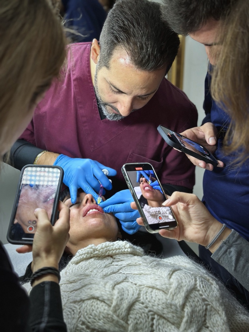 Il dott. Armenti tratta le labbra durante un corso, i medici intorno riprendono con il telefono